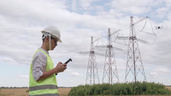 An Electrical Engineer Forcing a Drone To Inspect High Voltage Poles Before Starting a Project