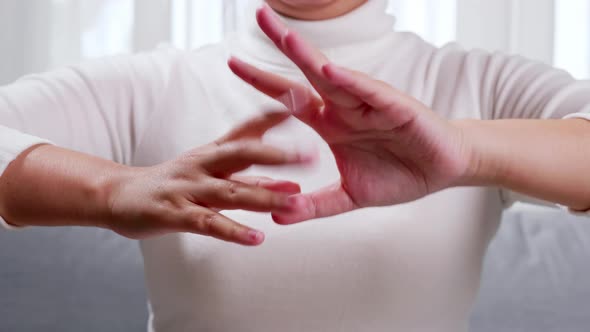 Young woman performing self hand massage during break in office.