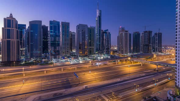 Aerial View of Jumeirah Lakes Towers Skyscrapers Night to Day Timelapse with Traffic on Sheikh Zayed