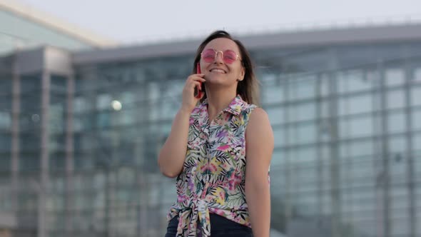 Girl Wearing Trendy Sunglasses Uses Her Phone. Using Smartphone for Call, Talk. Vacations, Tourism