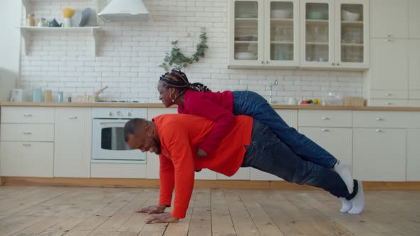 Black Single Father Doing Pushups with Daughter on Back