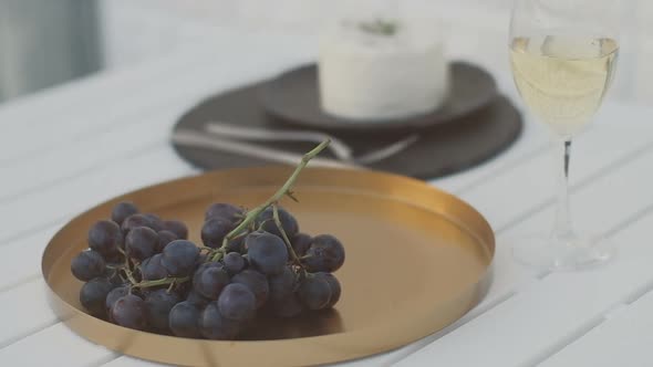 Dark grapes, wine and homemade cheese on a white table