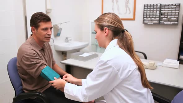 Smiling doctor measuring the blood pressure of his patient