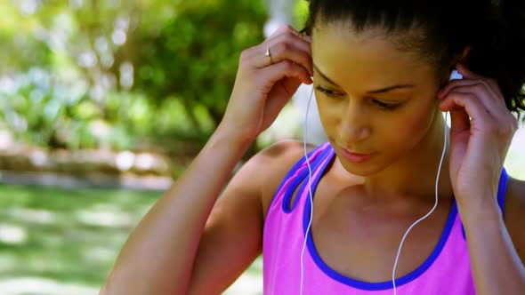 Female jogger woman adjusting her headphones in the park 4k