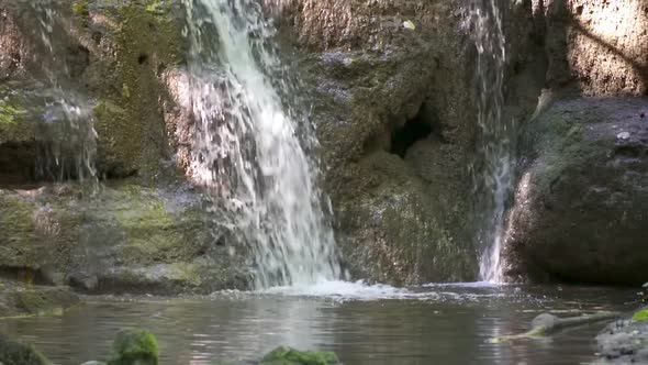 Beautiful Mountain Waterfall Falling down Over Mossy Rocks In The Forest in Switzerland.Slow motion