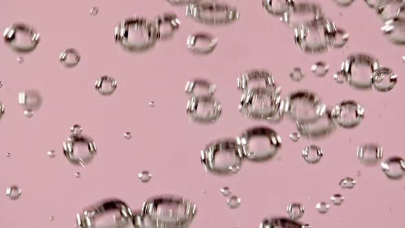Macro Shot of Air Bubbles in Water Rising Up on Light Pink Background