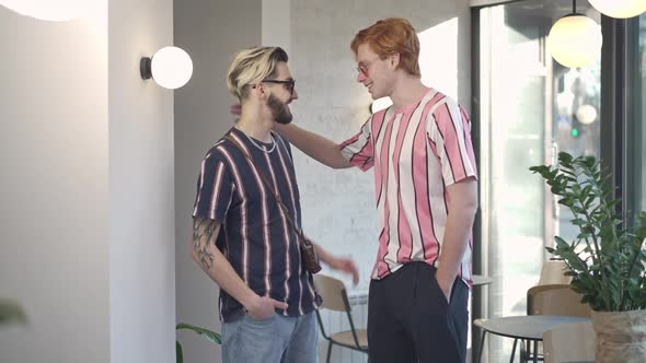 Two Positive Retro Men Tapping Shoulders Turning to Camera Smiling Posing Indoors in Vintage Coffee