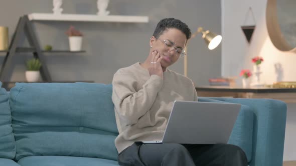 African Woman with Laptop Having Toothache on Sofa