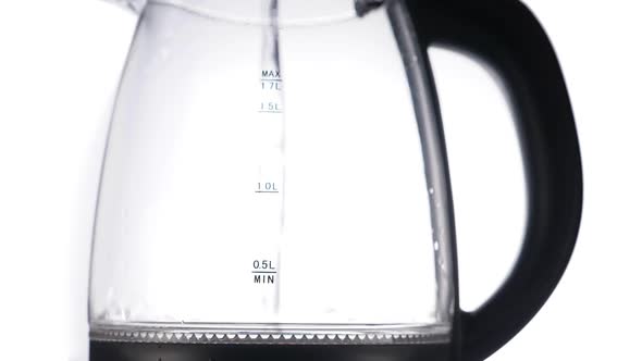 Pouring Water in Glass Kettle on White Background