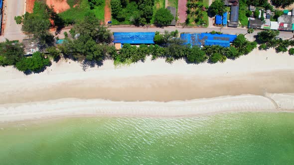 Aerial top view over city and sandy beach. coconut trees.