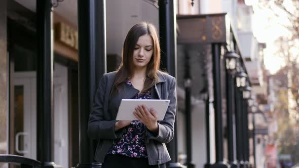 Portrait of the Beautiful Young Businesswoman Which Use the Tablet Device on the Street in the