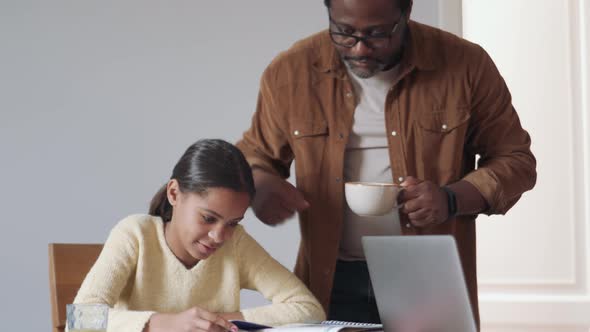 Cheerful daughter doing homework with her father