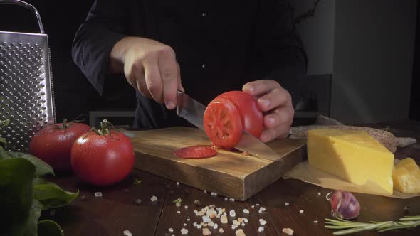 Chef Cuts Ripe Red Tomato in a Circles on the Wooden Board By the Sharp Knife, Ingredients