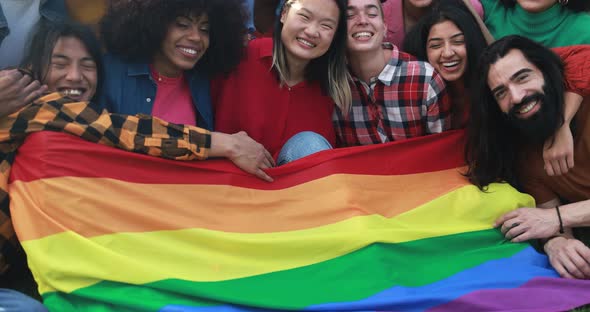 Diverse people having fun holding LGBT rainbow flag outdoor