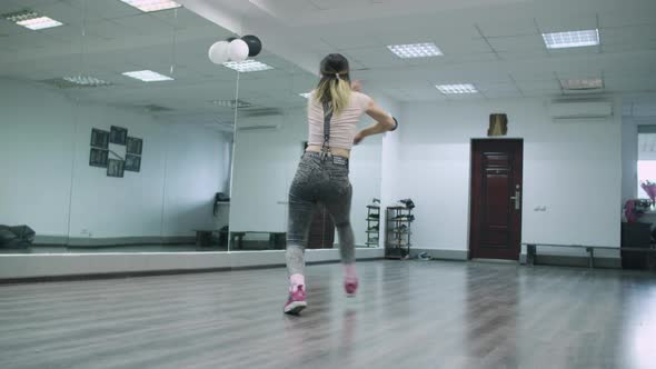 Caucasian female dancer choreographer performing hiphop animation in a dance studio against the mirr