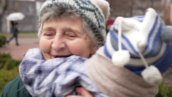 Great Grandmother Holds On Hands Her Great Grandson. Slow Motion. Winter Snow Falling