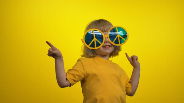 Sweet Little Girl with Short Hair in Funny Yellow Hippie Sunglasses is Dancing