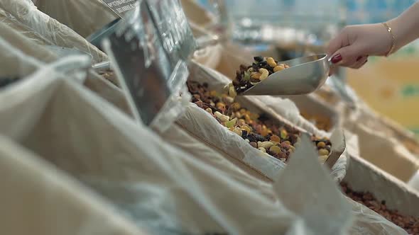 Young Girl Pours Dried Fruit Into a Package