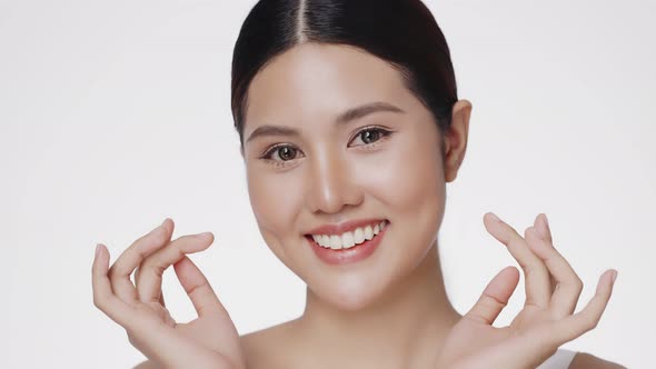 Close up portrait smiling young Asian girl massaging her beautiful face.