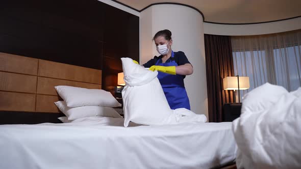 Hotel Maid in Mask and Gloves Changing Bed Linen