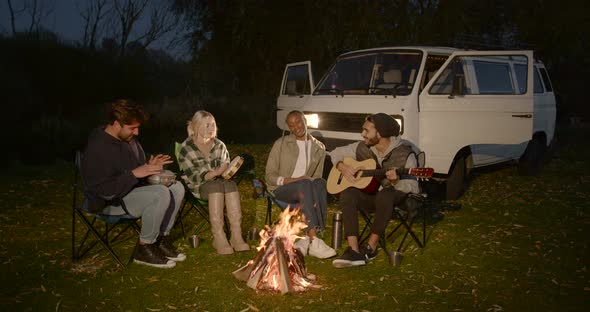 Four Young Tourists are Sitting on Chairs By the Fire