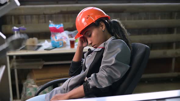A young black female worker in heavy production fell asleep at her workplace