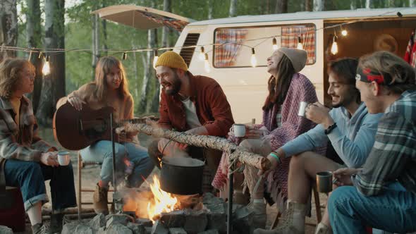 Young Happy Friends Chatting around Campfire