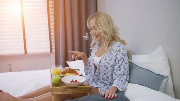 Attractive Young Woman in Shirt Having Breakfast While Sitting on Bed with Tray