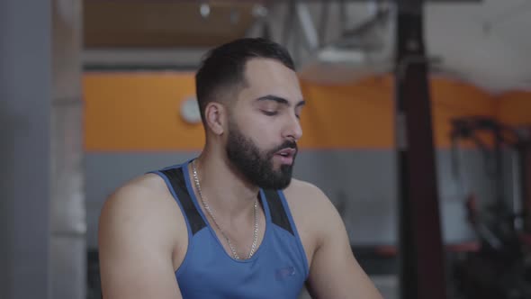 Portrait of Tired Satisfied Middle Eastern Sportsman Sighing, Wiping Forehead and Drinking Water