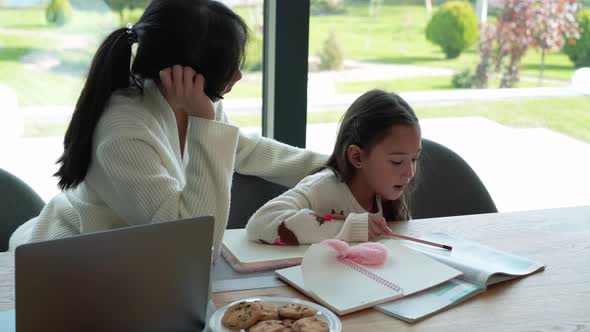 Handsome Asian mother helps her daughter doing homework