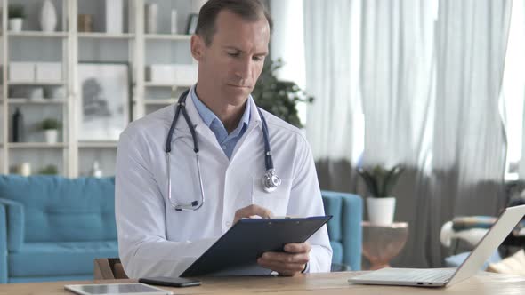Senior Doctor Reading Medical Documents of Patient