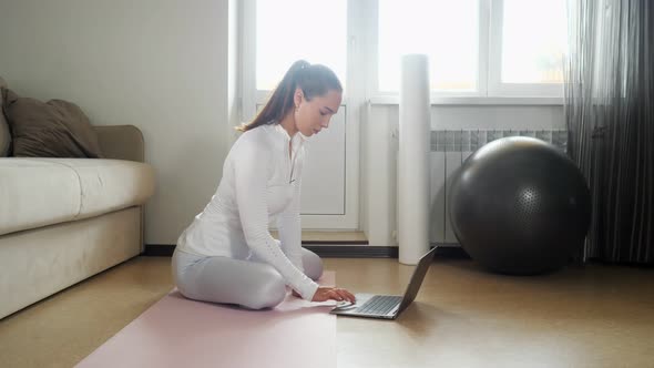 Girl Surfs Internet with Laptop To Find Exercises in Room