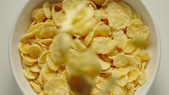 Cornflakes Falling Into A White Bowl