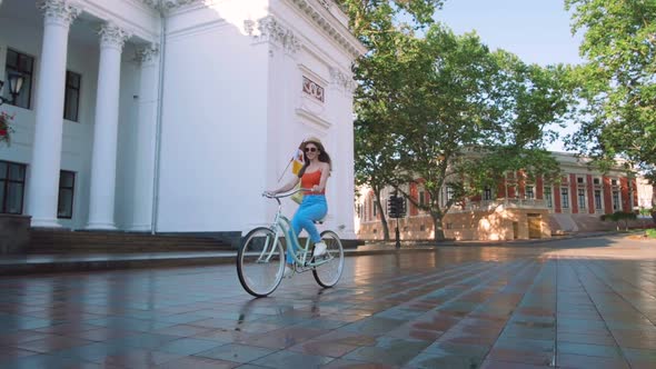 Young Attractive Woman in Hat Riding on Vintage Bike in City Center and Having Some Fun