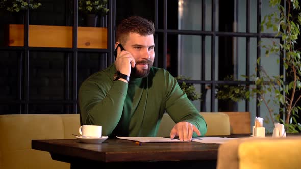 Modern Guy Calling By Smartphone in a Caffe