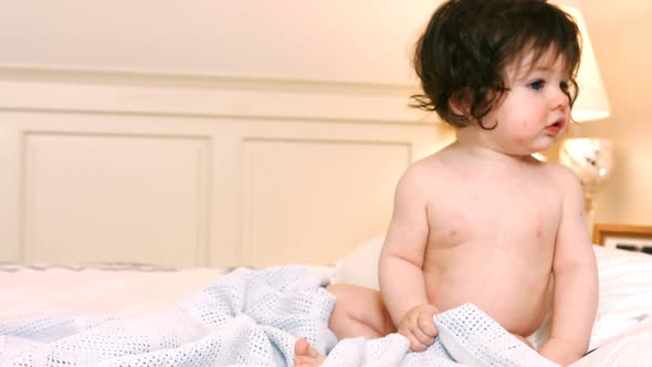 Cute baby girl sitting on bed