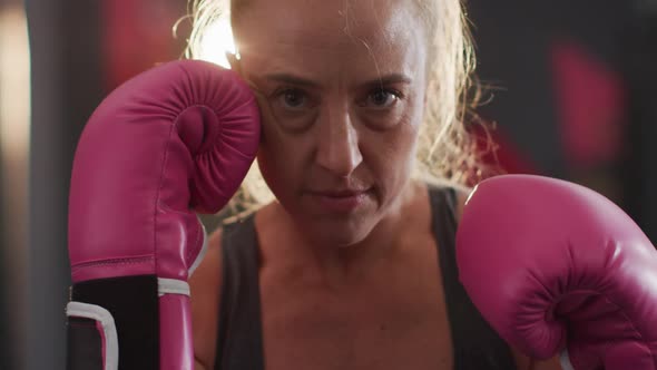 Close up of female boxer wearing boxing gloves practicing her punches at the gym