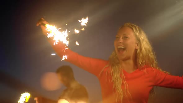 Couple dancing with sparklers on beach at dusk 