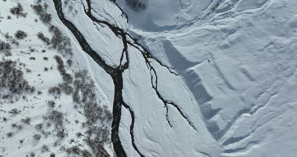Gudauri, Georgia - January 17 2022: aerial view of the the river flowing in the snowy mountains
