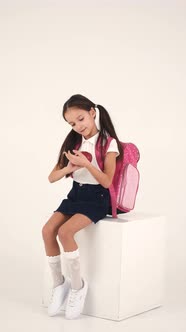 Cheerful Girl with Backpack Sitting in Studio