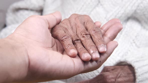 Detail Shot of Young Man Holding Hand of a Senior Women