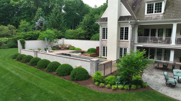 Close up of mansions patio and pool. Beautiful green grass on quiet estate surrounded by trees. Luxu