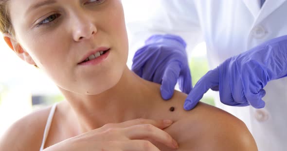 Woman therapist pointing a mole of her patient