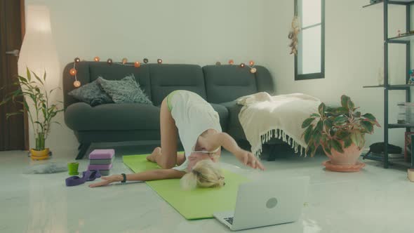 Woman Doing Stretching on the Floor at Home in Front of Her Laptop Online Yoga Class