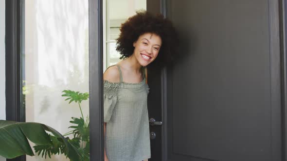 Mixed race woman opening a entrance door and looking at camera