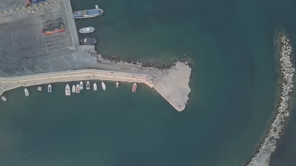 Aerial view of boats moored in harbour near lighthouse and breakwater wall Rethymno Crete Greece