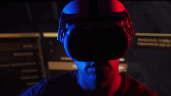 Young Man Plays a Game in a VR Helmet Under RedBlue Light