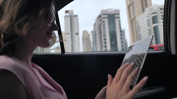 A Girl in a Car Works with a Tablet While Driving in Dubai