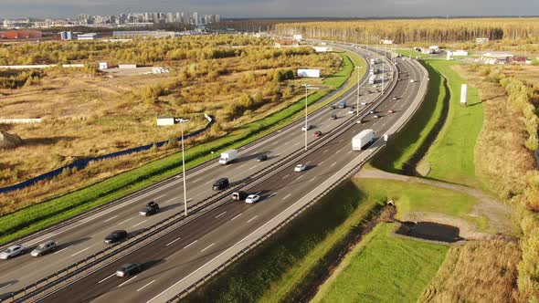 Highway with Cars and Trucks Driving Past Forest and Meadow