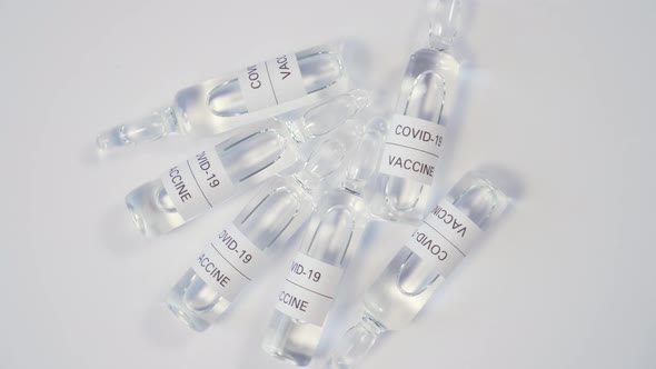 Six medical glass ampoules with a vaccine from COVID-19 on a wooden surface. 